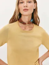 Blusa color amarillo mostaza de tejido de punto fino, con cuello redondo y mangas cortas.