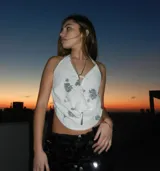 Top blanco con estampado floral plateado, escote halter y cierre frontal con cordones.