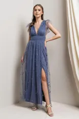 Vestido largo de fiesta color azul acero, con escote en V, mangas cortas de tul fruncido y falda de tul con abertura lateral y estampado de estrellas plateadas.