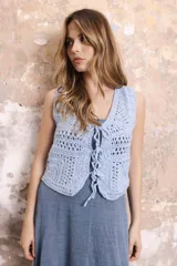 Chaleco corto tejido a crochet color verde oliva, con escote en V y cierre frontal con lazos.