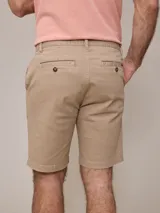 Bermuda color beige, de corte recto y largo hasta la rodilla.