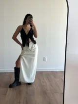 Conjunto de top negro con tirantes finos y falda larga blanca con tajo lateral.