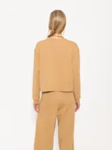 Buzo de punto color crema con lurex y mangas largas con puños ajustados.