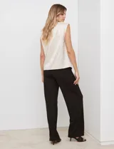 Blusa de gasa color beige con textura labrada, sin mangas, con hombreras internas y abertura en la espalda con botón.