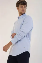 Camisa de hombre color crema, de corte clásico, con cuello abotonado y mangas largas.