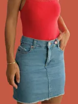 Minifalda de jean azul con bolsillos traseros y ruedo desflecado.