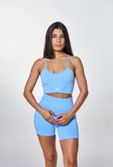 Conjunto deportivo celeste compuesto por un top con breteles finos y logo 'bk.' estampado en blanco, y un short de calce ajustado.