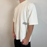 Remera blanca de corte oversize con estampa de hongos y texto en la espalda.