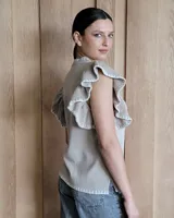 Musculosa blanca de punto con cuello redondo y mangas con volados.