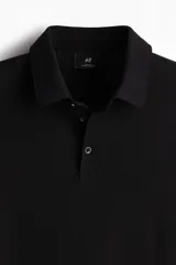 Chomba negra de piqué de algodón, corte slim fit, con cuello clásico, tapeta de dos botones y mangas cortas.
