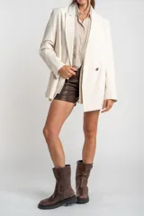 Blazer color crema, de corte oversize, con solapas de muesca, cierre con doble botón y bolsillos laterales con solapa.