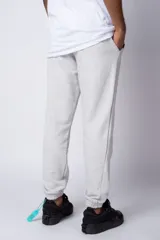Pantalón de jogging gris claro con puños elásticos, cintura con cordón ajustable y estampado con motivos geométricos en la pierna izquierda.