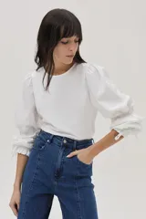 Blusa blanca de mangas largas abullonadas con puños elásticos y lazos.
