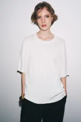 Remera blanca de punto liso, corte amplio, cuello redondo y manga corta.