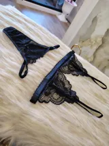 Conjunto de lencería negro de encaje, compuesto por un bralette con breteles regulables y una tanga regulable con corte cola less y entrepierna de algodón.