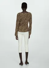 Blusa de tejido fluido color crema con estampado animal print negro, cuello en V y mangas largas abullonadas.