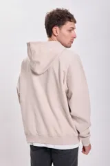 Canguro deportivo color beige con capucha, corte holgado y bolsillo tipo parche en el pecho.