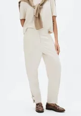 Pantalón de vestir color blanco hueso, de corte recto y tiro alto. Presenta detalle de botón en el tobillo.