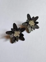 Par de aros con forma de flor de pétalos negros con glitter y centro con strass plateado.