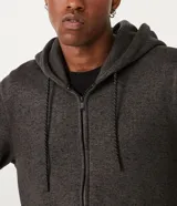 Campera de algodón gris oscuro jaspeado, con cierre frontal de cremallera, capucha con cordones trenzados y bolsillo canguro.