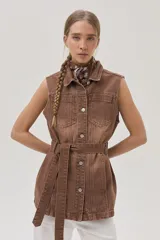 Chaleco largo marrón de algodón con cuello camisero, cierre frontal con botones, bolsillos laterales y lazo ajustable en la cintura.