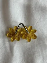 Par de aros tipo argolla con dije colgante de flor amarilla con glitter.