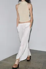Top color crema de tejido de punto con cuello halter fluido y hombros descubiertos. Detalle de hilo metalizado.