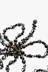 Par de aros colgantes con forma de flor, hechos de cuentas negras.