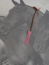 Collar con cordón de cuero marrón y dije cuadrado de metal con flecos rojos.