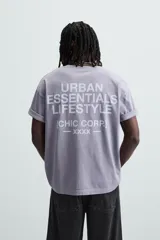 Camiseta gris de corte holgado, cuello redondo y manga corta. Estampado con la frase "Live in Style Everyday" en el frente.