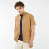 Camisa color beige de manga corta con cuello mao y cierre frontal con botones.