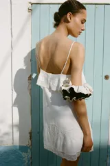 Vestido corto blanco con tirantes finos ajustables, escote recto, detalle de bordados y volantes, tejido elástico tipo nido de abeja y forro interior combinado a tono.