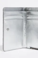 Billetera plateada de piel con textura tipo escamas, cierre de cremallera y logo metálico de la marca Bimba y Lola.