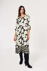 Vestido midi con estampado de flores blancas sobre fondo negro, mangas 3/4 y corte evasé.