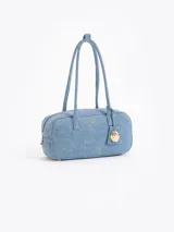 Cartera tipo baulito color celeste, confeccionada en denim, con manijas de tela. Incluye un charm colgante de mariquita dorada.