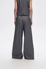 Pantalón gris de poliéster, corte ancho y tiro alto, con bolsillos laterales.