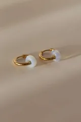 Par de aros dorados tipo argolla con dije de piedra natural blanca.