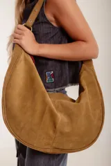 Cartera hobo grande de cuero descarne color marrón claro, con correa de hombro ajustable con hebilla metálica.