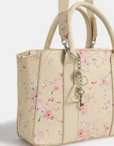 Cartera tipo tote color blanco crudo, con doble asa corta y correa larga regulable y desmontable. Incluye charm colgante con forma de corazón y cierre superior.