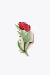 Pinza para el pelo color crema con forma de flor roja y hojas verdes en relieve.