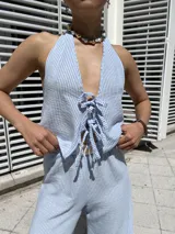 Top celeste a rayas verticales blancas, con escote halter y lazos ajustables en el frente y en la espalda.