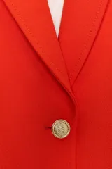 Blazer color rojo con cuello solapa, manga larga con hombreras, bolsillos delanteros con solapa y cierre frontal con botones dorados.