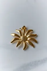 Collar con tiento negro y dije plateado en forma de flor con centro texturizado.