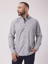 Camisa de manga larga a rayas verticales finas en tonos de gris y blanco, con cuello abotonado, cierre frontal con botones color madera y bolsillo en el pecho con logo bordado. Corte clásico.