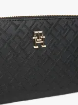 Billetera Tommy Hilfiger negra con diseño de monogramas TH en relieve y cierre de cremallera.