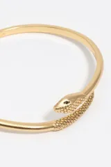 Pulsera rígida dorada con diseño envolvente de serpiente, con detalles de textura grabada en la cabeza y la cola.
