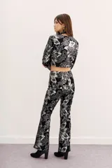 Pantalón de terciopelo negro con estampado floral plateado, corte acampanado y tiro alto.