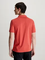 Chomba de piqué de algodón orgánico color ladrillo, corte slim, cuello clásico con dos botones, mangas cortas con puños de punto y logo bordado en el pecho.