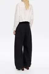 Pantalón negro de tejido técnico con corte barrel, cierre de corchete oculto y cremallera, trabillas ajustables en cintura y bajo, bolsillos delanteros en costuras y bolsillos con vivo en la parte posterior.