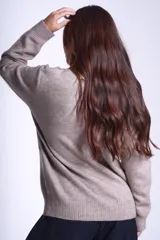 Sweater color beige de tejido de punto con cuello alto y mangas largas. Presenta detalles de ochos en diagonal en los laterales.